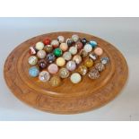 A carved hardwood solitaire board with polished and labelled geological specimen marble balls
