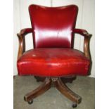 An early 20th century revolving desk chair, with faux leather upholstered serpentine seat, back