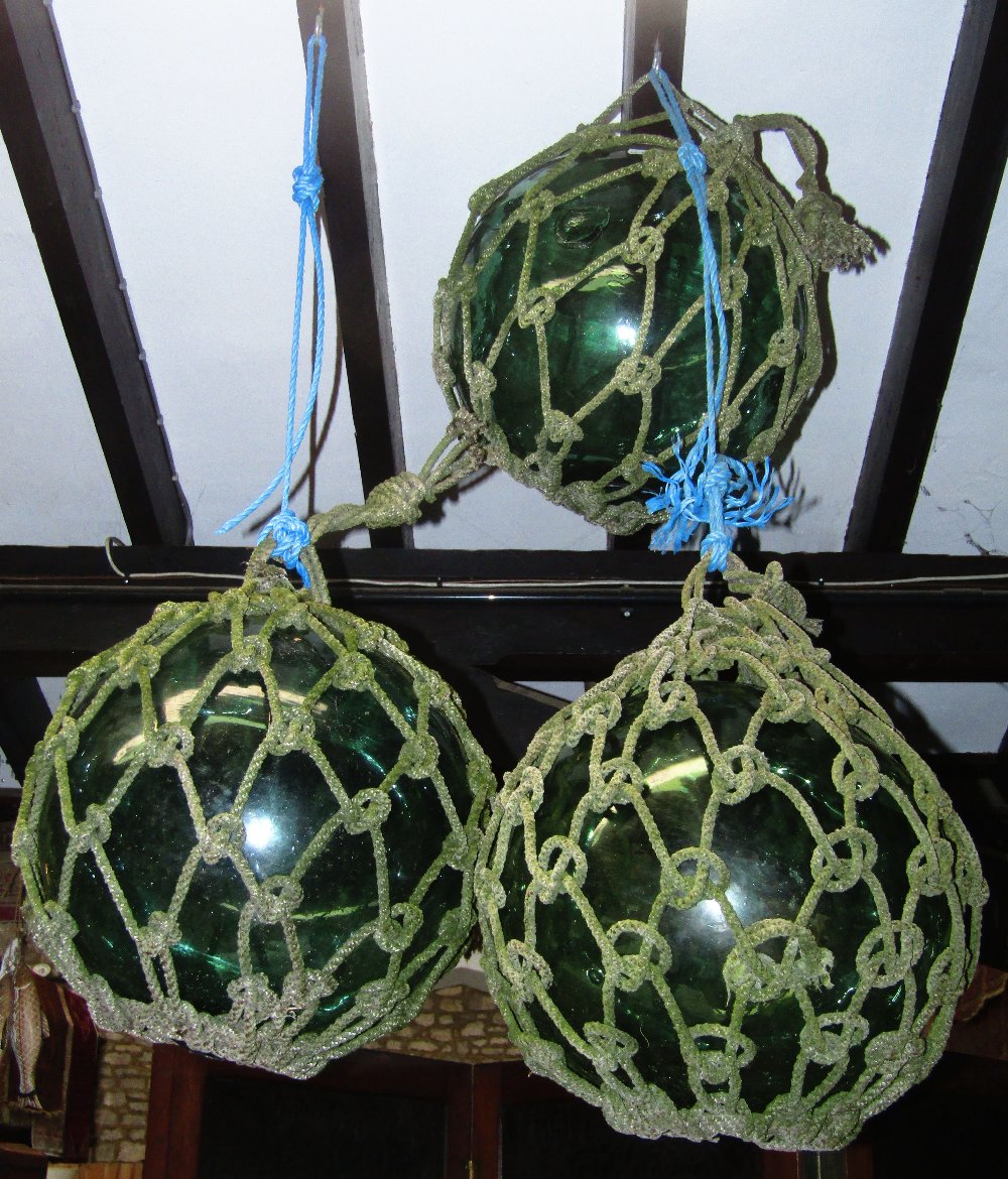 Three large vintage green tinted hand blown rope twist encased fishing floats 18 inches in