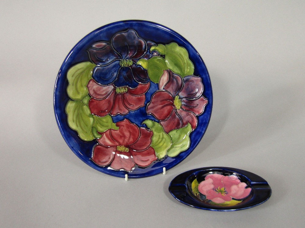 A Moorcroft blue ground plate with red and purple clematis pattern decoration and with paper label