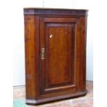 A small Georgian oak hanging corner cupboard, the panelled door with crossbanded borders and star