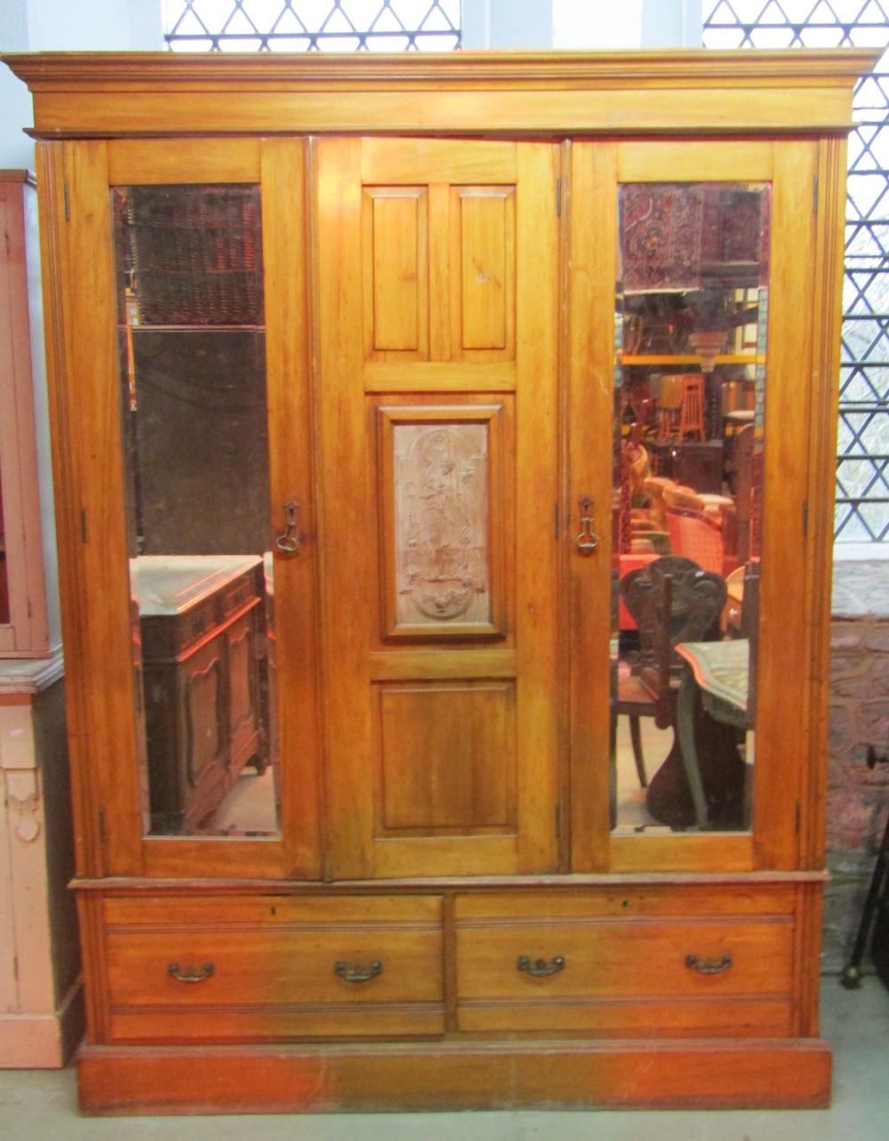 A late Victorian/Edwardian walnut triple wardrobe with moulded cornice over three, three quarter