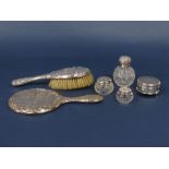 A collection of silver dressing items to include brush mirror and silver topped jar, all embossed