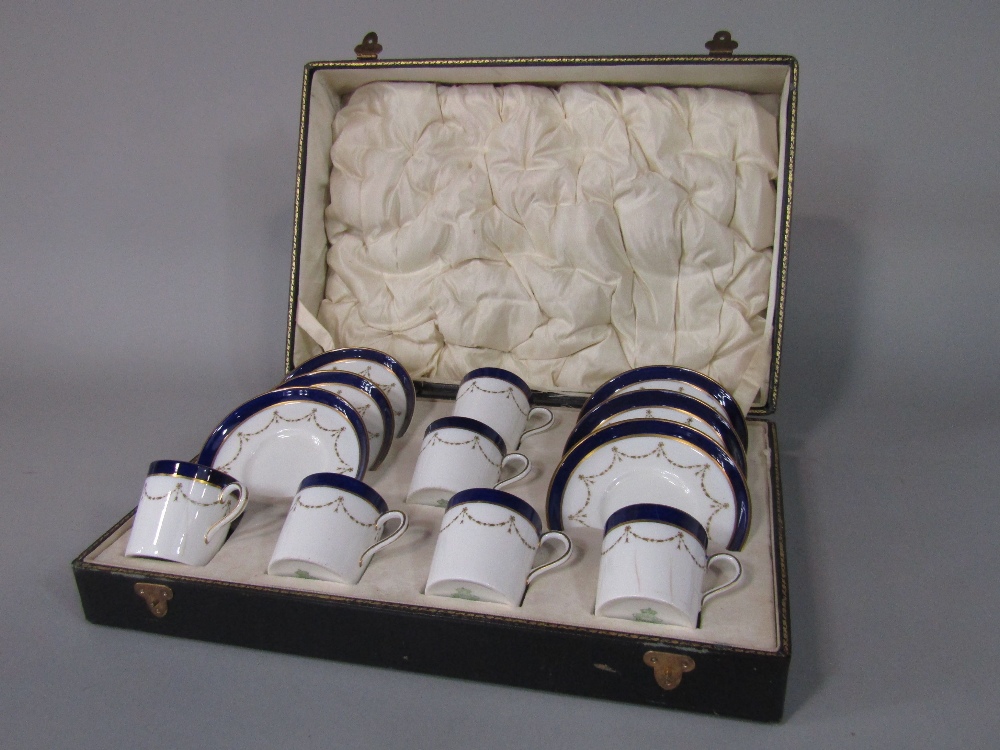A cased set of six Aynsley coffee cans and saucers with blue and gilt decoration and with printed
