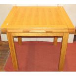 A contemporary oak draw leaf dining table, raised on four square cut supports, 91cm square when