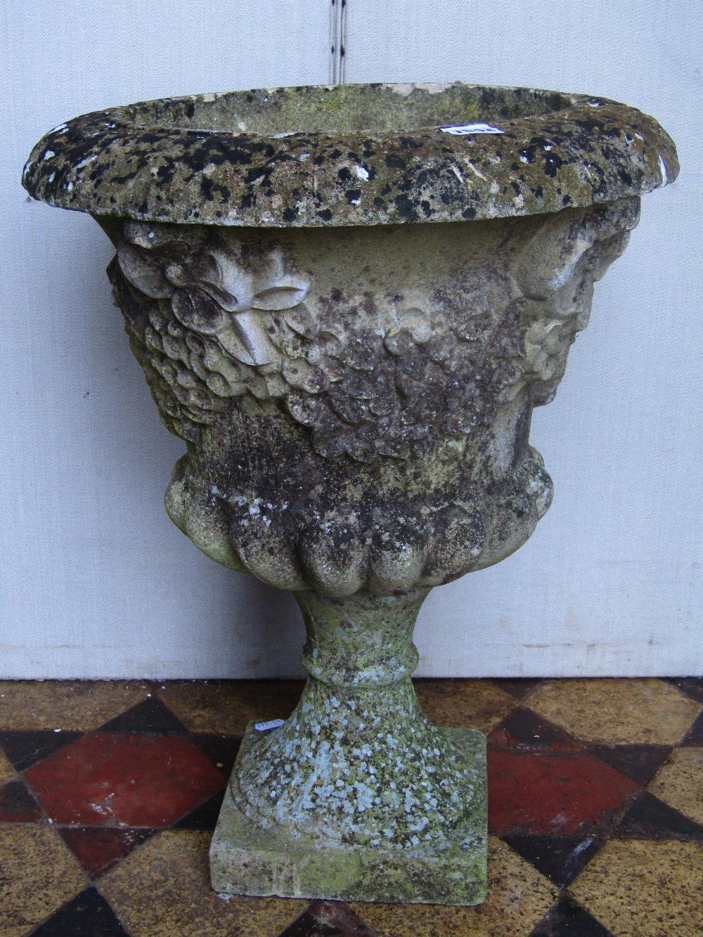 A weathered cast composition stone garden urn, with flared rim, lobed body raised relief detail