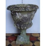 A weathered cast composition stone garden urn, with flared rim, lobed body raised relief detail