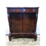 A Victorian mahogany side cupboard, the serpentine front fitted with a shallow frieze drawer, over a