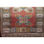 A Turkish wool rug with pastel shades, salmon pink ground, overlaid with abstract and geometric