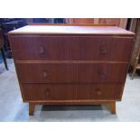 A Meridew teak bedroom chest of three long drawers, with dished circular handles, raised on