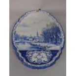 A 19th century Delft plaque of shaped oval form with painted winter canal scape and with painted