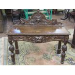 A Victorian oak hall table of narrow rectangular form with heavily carved detail, including mask,