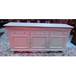 A dresser base, with light green painted finish, enclosed by three fielded panelled doors and