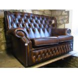 A contemporary brown leather upholstered two seat sofa with rolled arms, slightly winged back,