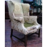 A Georgian style wing chair with scrolled arms, raised on square cut supports with repeating