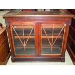 A 19th century mahogany side cabinet enclosed by a pair of glazed panelled doors flanked by split