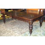 A Victorian oak wind out extending dining table of rectangular form with rounded corners and two