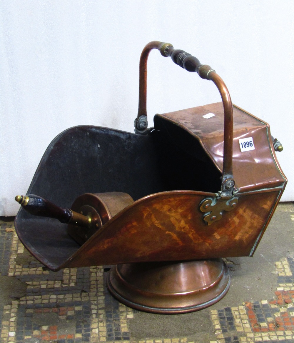 A 19th century copper helmet shaped coal scuttle with turned wooden hand grips together with