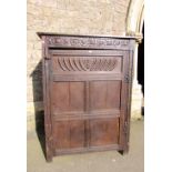 An 18th century oak side cupboard set beneath a panelled framework with carved frieze, 98cm wide x