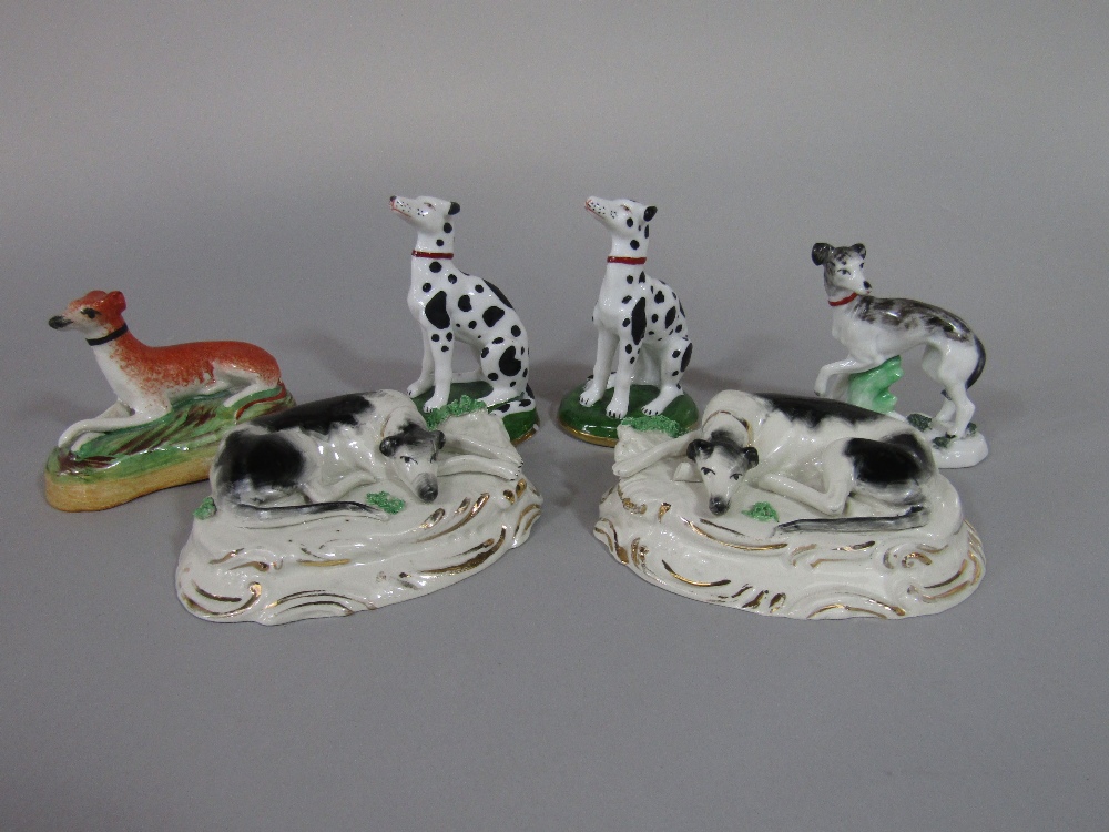 A pair of 19th century Staffordshire models of recumbent black and white greyhounds raised on oval