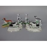 A pair of 19th century Staffordshire models of recumbent black and white greyhounds raised on oval
