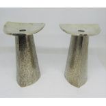 A pair of contemporary silver candlesticks with tricorn bases and bark effect finish, supporting