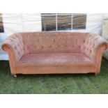 A two seat Chesterfield sofa, with pink ground repeating floral patterned upholstered finish and