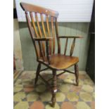 A traditional Windsor stained elm and beechwood lathe back armchair with saddle shaped seat raised