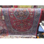 A cotton rug in the Persian style with red ground, central medallion and overall floral detail,