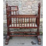 A 19thy century mahogany cradle with turned spindle framework, and arched canopy, raised on reeded