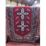 A red ground Persian style rug with medallion to the centre within repeating borders, 130 x 75 cm