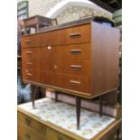A contemporary teak wood chest of four long drawers with cup handles on turned and tapering