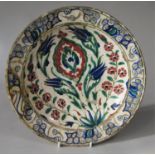 A early Persian dish with polychrome painted stylised tulip decoration, 29cm diameter (af)