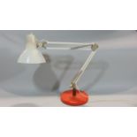 A vintage anglepoise lamp with circular weighted base in red, the remainder in white