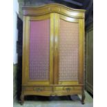 A medium to light oak armoire with moulded arched cornice over a pair of three quarter length