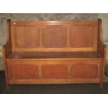 A panelled oak settle with hinged box seat, 138 cm long x 45 cm deep x 95 cm in height, together