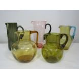 A collection of citrine type glass jugs, one with blue handle, together with a further smoked