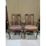 A pair of queen Anne style walnut elbow chairs with carved vase shaped splats, with hide upholstered