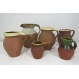 A collection of five terracotta pottery jugs with glazed rims and handles, possibly by Verwood