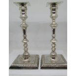 A pair of George II style silver candlesticks, with knopped stems, raised on square cut bases with