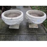 A pair of composition stone garden urns, of squat circular form with raised relief tied ribbon and