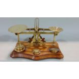A set of Victorian brass and oak balance postal scales by Sampson Mordan & co compete with seven