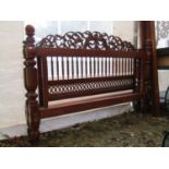 A hardwood double bedstead, possibly Indian, with turned supports carved scrolling foliate pediment,