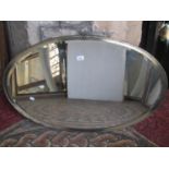 An Edwardian wall mirror of oval form, with bevelled edge plate within a cast metal frame, with