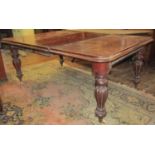 A Victorian mahogany extending dining table, raised on four fluted supports, with two additional