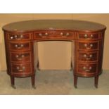 An inlaid Edwardian mahogany kidney shaped writing desk with tooled sage green coloured inset