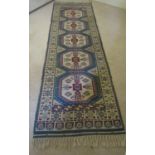 A Turkey wool runner with mid blue ground, several repeating hexagonal medallions within white
