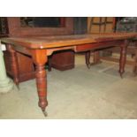 A Edwardian walnut wind out extending dining table of rectangular form with canted corners and