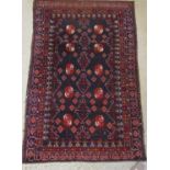 A Persian wool rug with dark blue ground with further geometric detail principally in a red