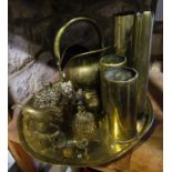 A circular brass tray with engraved detail, brass shell cases, small brass coal scuttle and